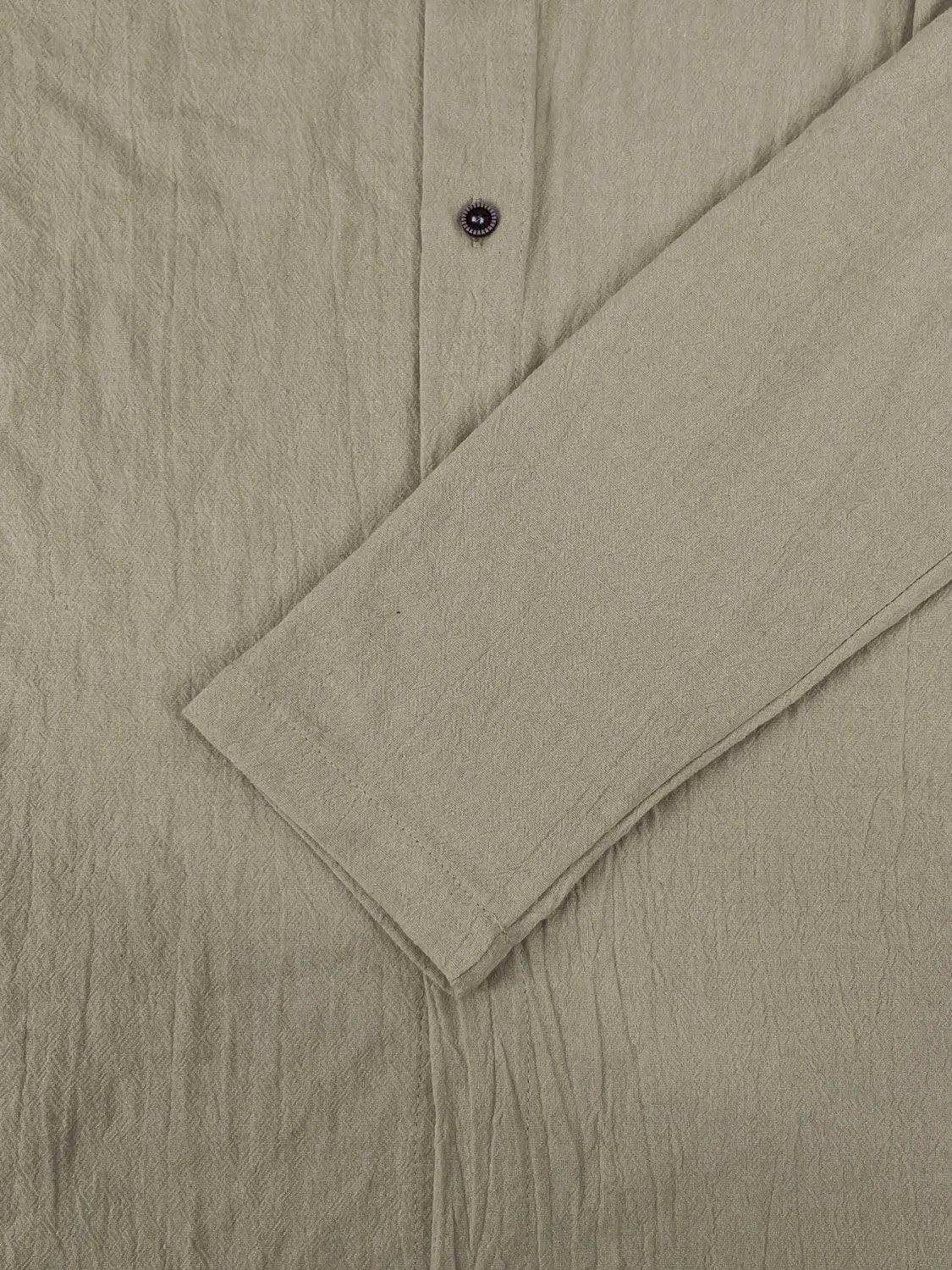 Camisa de cárdigan con capucha ligera para hombre en lino color beige, con tejido ligeramente texturizado y un solo botón oscuro en el cuello.