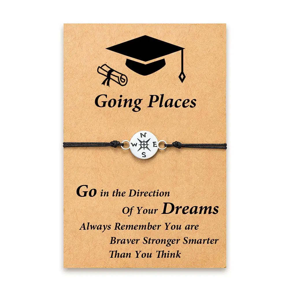 Silver compass charm graduation adventure cord bracelet with black cord displayed on a kraft paper card featuring graduation-themed graphics and inspirational text.