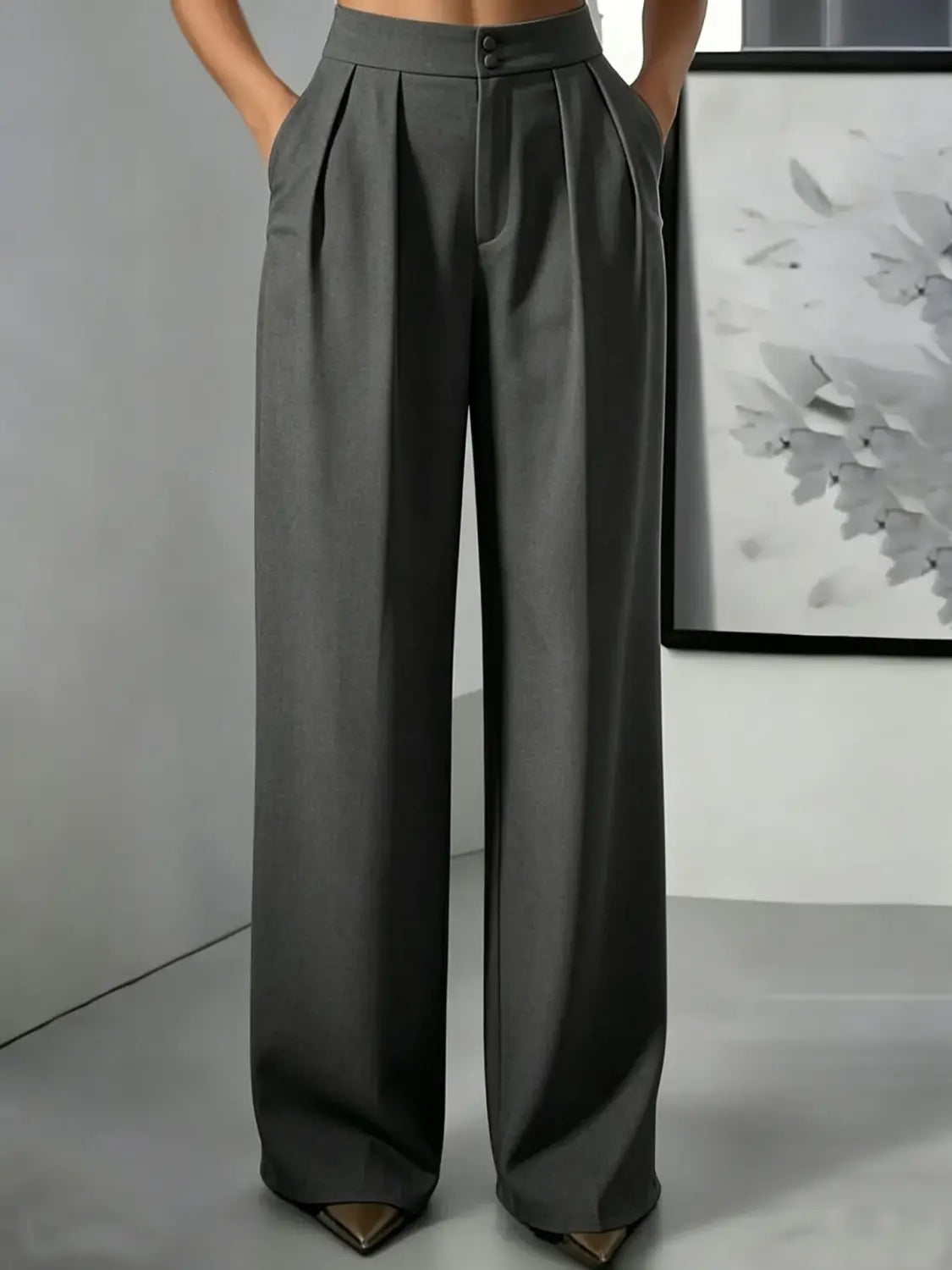 Pantalons à jambes larges et taille haute dans un tissu gris anthracite élégant, avec un devant plissé et une fermeture à boutons, conçus pour une coupe à la fois stylée et confortable.