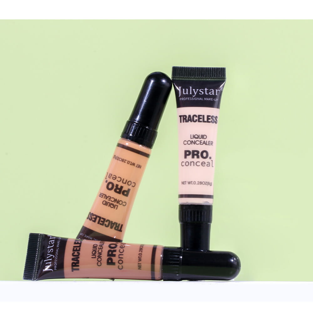Three tubes of Julystar traceless pro tattoo concealer with black caps and beige and pinkish labels on a light green background.