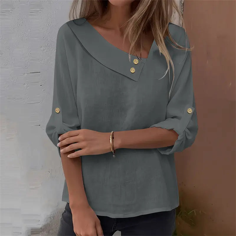 A soft sage green asymmetric button blouse with a collar and three-quarter sleeves featuring gold-tone buttons at the neckline and cuffs.