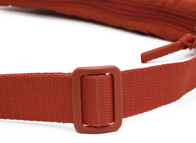red woven nylon fabric belt with a matching rectangular plastic buckle on a dumpling messenger bag curved crossbody strap