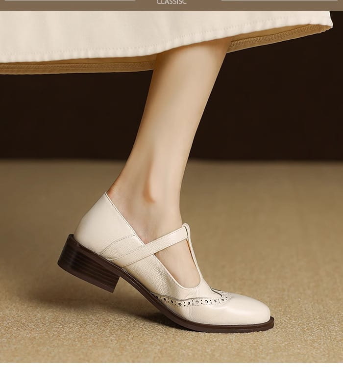 Cremefarbene Leder-Brogue-Mary-Jane-Pumps mit klobigem Absatz mit dunkelbraunem Blockabsatz und dekorativen, perforierten Details am Vorderteil.