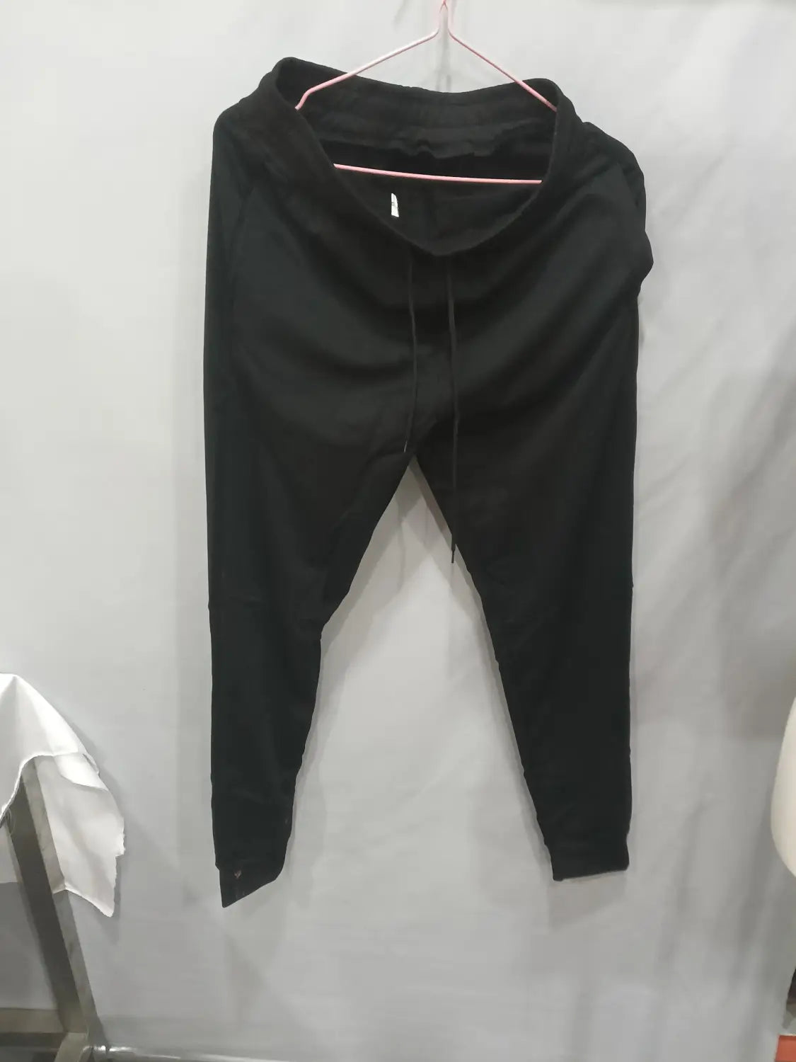 men’s athletic training jogger pants in black drawstring design hanging on a pink hanger.