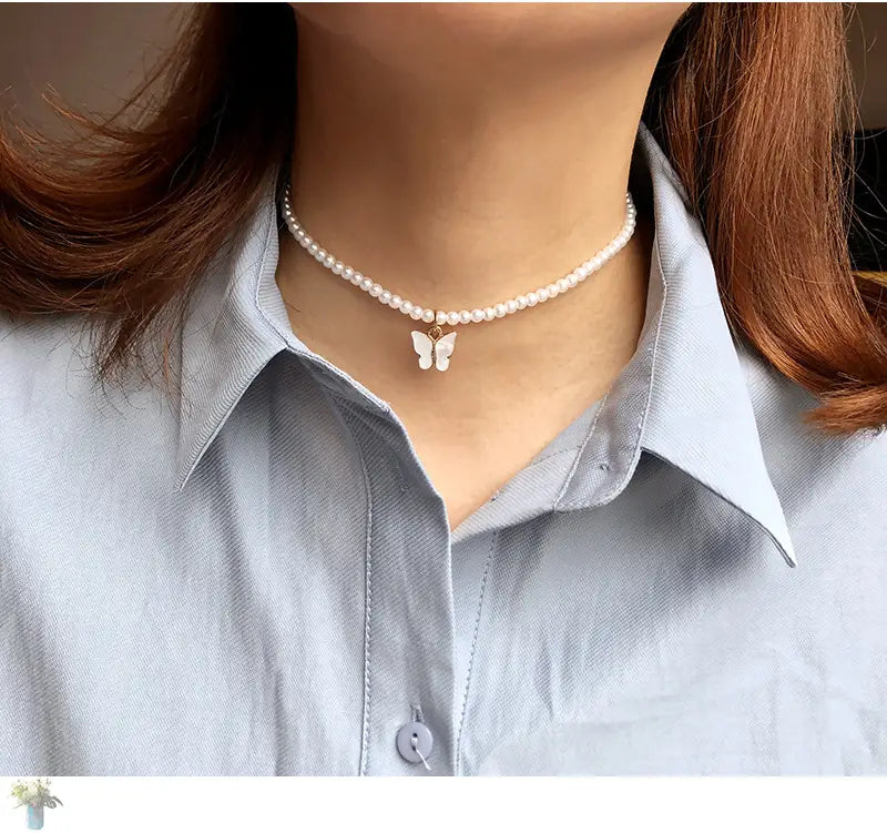 A delicate pearl choker necklace featuring a small white butterfly pendant in an elegant pearl butterfly charm choker necklace design.