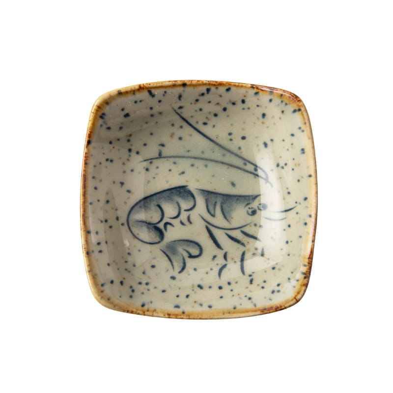 A square ceramic sea creature sauce dish with a speckled beige glaze and hand-painted blue shrimp design in Japanese style.
