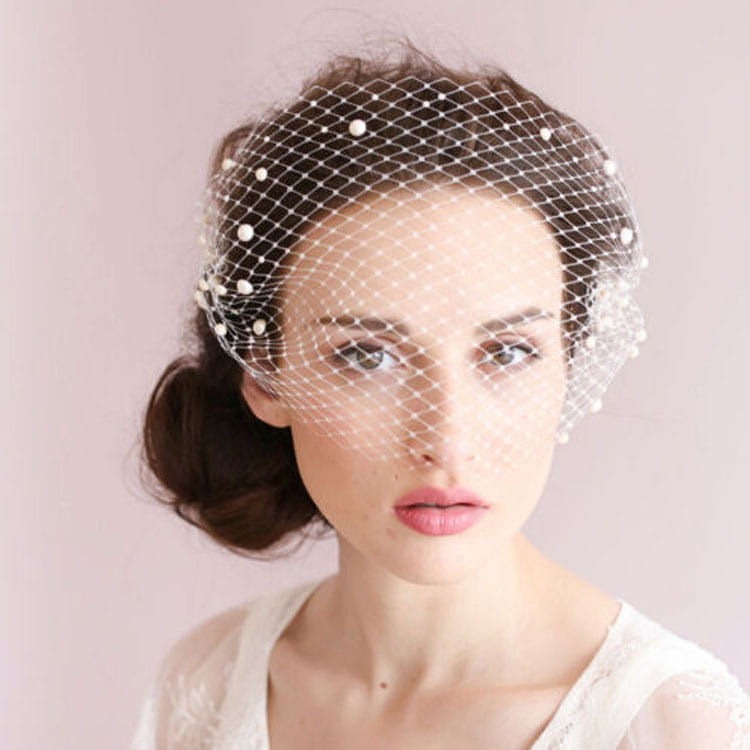 Short pearl beaded mesh bridal veil in delicate white featuring a fine mesh design with small pearl beads along its edges and a gold hair comb.