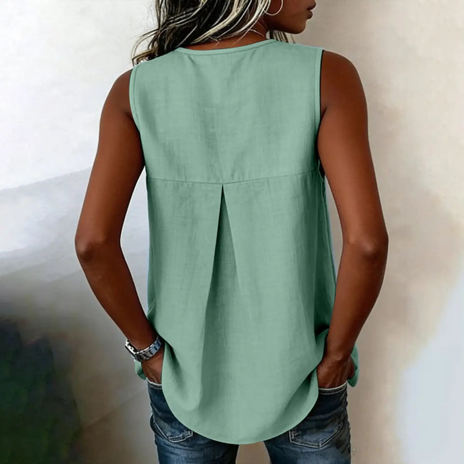 A soft mint green sleeveless tie side button down blouse with a relaxed fit and subtle pleating shown from the back side.