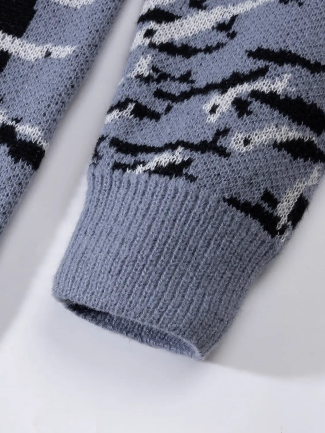 Ein grauer Strickärmel des Orca-Strickpullovers im Casual-koreanischen Pullover-Stil mit einem abstrakten Schwarz-Weiß-Muster.