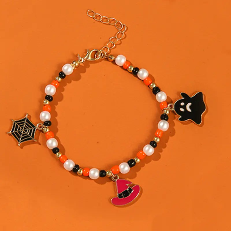 Halloween ghost and pumpkin beaded jewelry set featuring a Halloween-themed bracelet with white pearls, orange and black beads, gold-tone chain clasp, and dangling spiderweb, ghost, and witch hat charms.