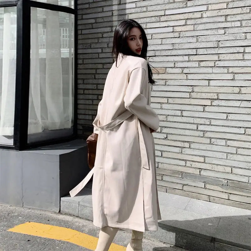 beige faux leather trench coat with belted waist and long sleeves designed as a windbreaker jacket