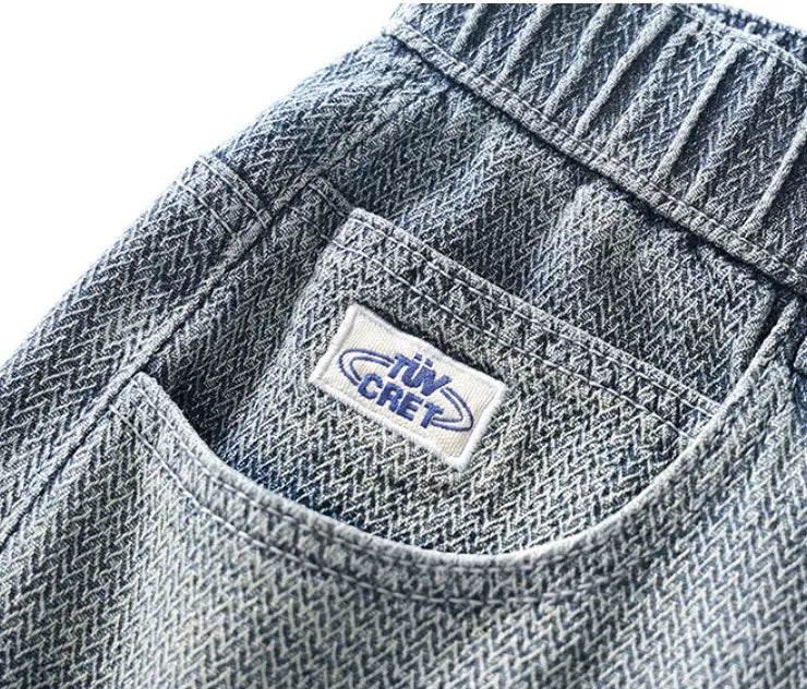 Men’s elastic waist light wash denim shorts in gray herringbone pattern featuring a white label with blue tuv cret branding.