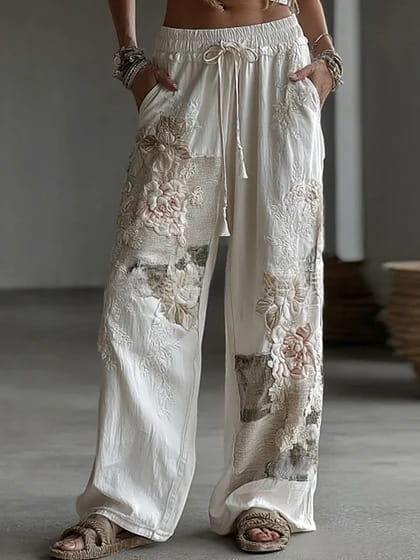 Pantalon décontracté ample à jambes larges à imprimé numérique blanc, présentant une broderie en assemblage ornée de détails floraux et d’appliqués texturés.