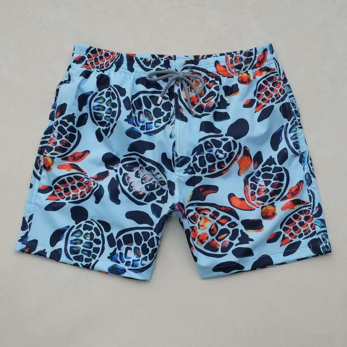 Light blue quick drying beach pants featuring a vibrant pattern of stylized turtles in navy orange and red hues.