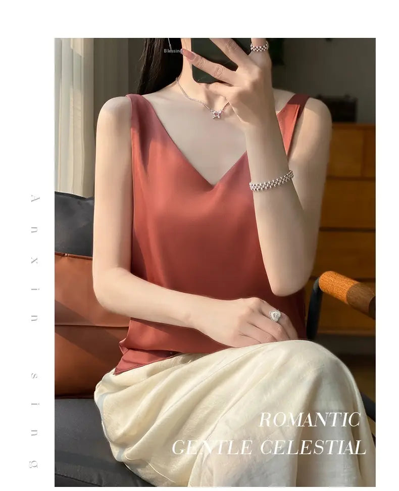 A soft rust-colored silky satin v-neck camisole top with delicate straps and a deep neckline.