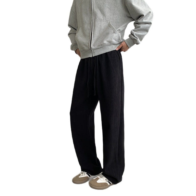 Black wide leg corduroy drawstring pants featuring loose-fitting trousers with a drawstring waistband.