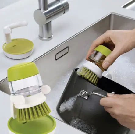 Soap dispensing dish brush in green and white with a clear plastic body, bristle head, and a non slip storage base.