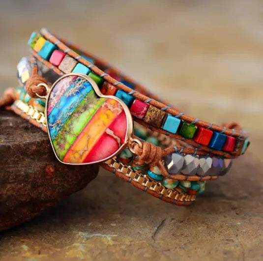 A vibrant multi-strand leather wrap bracelet featuring a colorful rainbow heart-shaped imperial stone pendant with intricate beaded detailing.