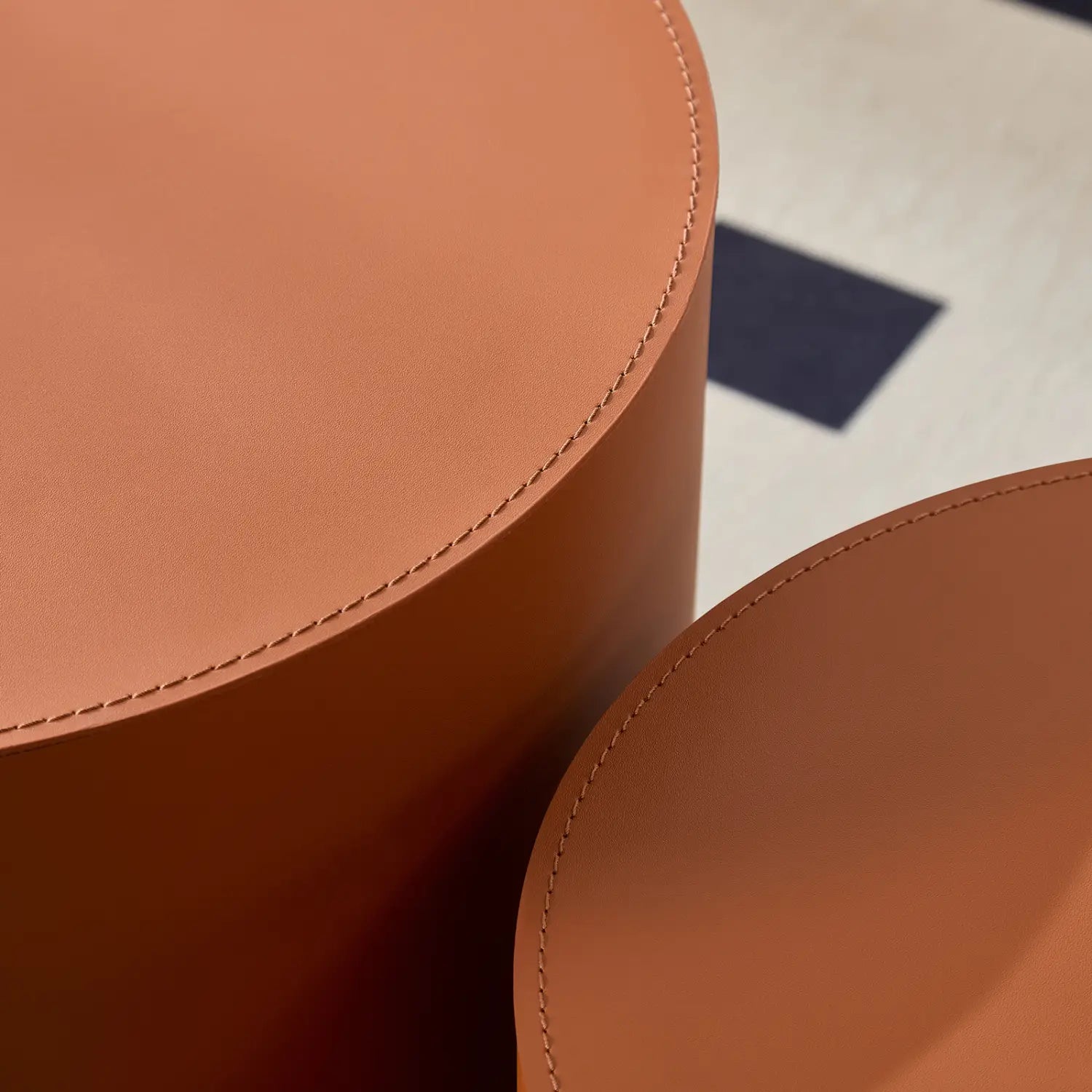 Taburetes cilíndricos de cuero color ante con costura precisa a lo largo de los bordes, del conjunto de mesa de centro redonda de cuero de silla color naranja