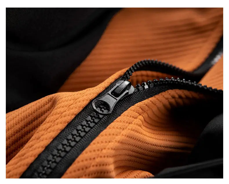 Una cremallera negra con acabado mate recorre la costura de una tela acanalada naranja en la chaqueta acolchada tipo puffer para hombre con estampado de letras.