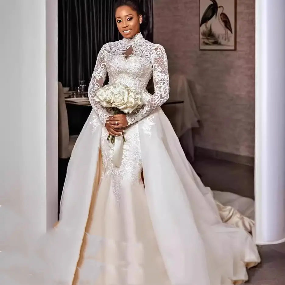 A white lace floral lace stand collar long sleeve wedding gown with intricate embroidery along the bodice and skirt.