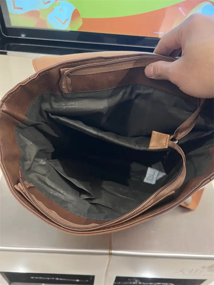 Brown leather crossbody bag with black interior lining and zipper compartments featured in vintage leather college backpack large capacity travel bag.
