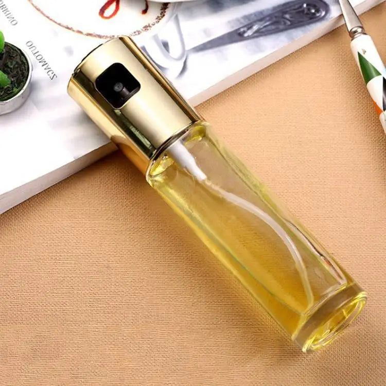 oil spray bottle for cooking leakproof glass sprayer featuring a gold-toned spray top and clear glass body filled with yellow liquid.