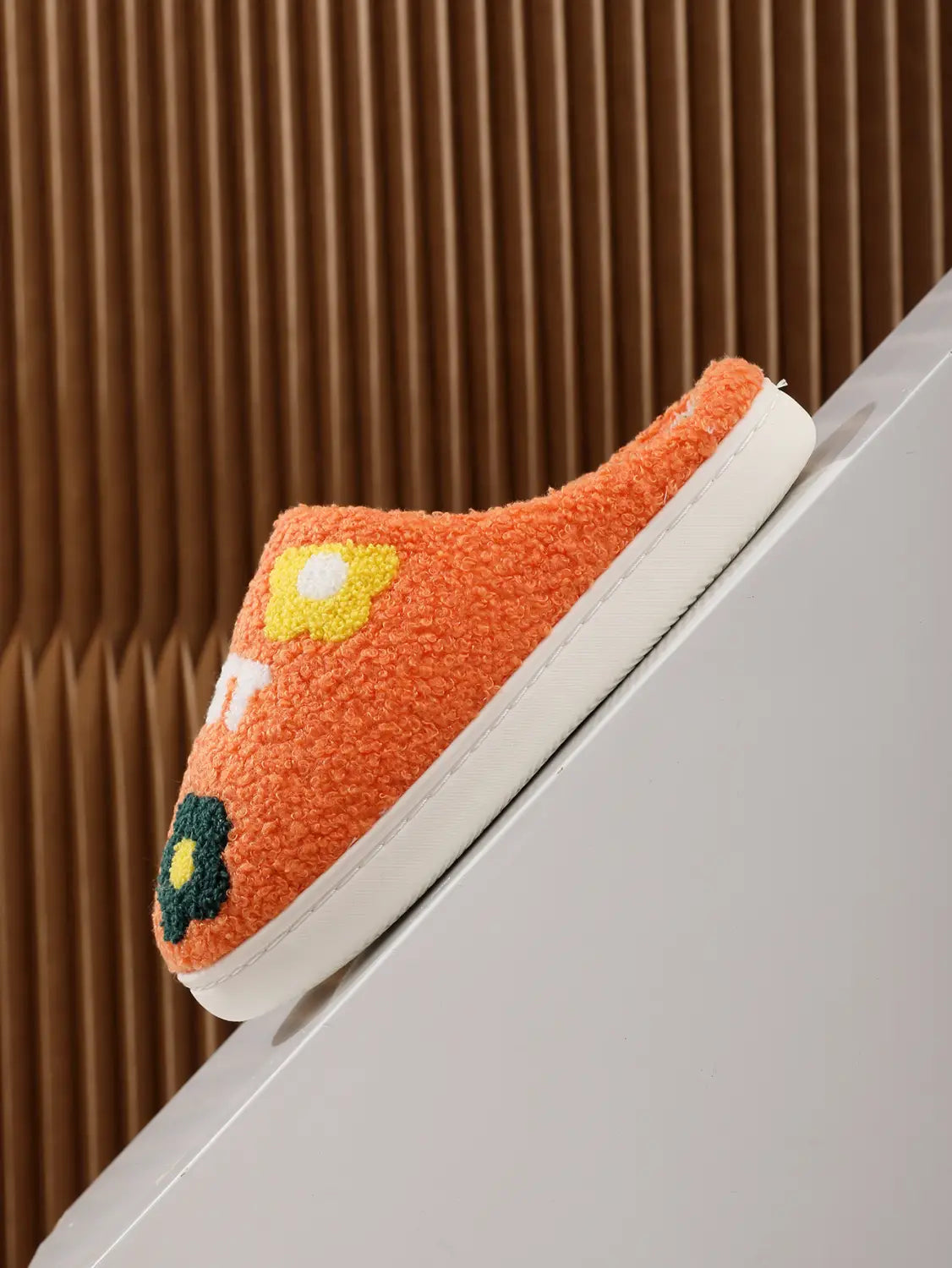 orange fuzzy plush floral cotton slipper with embroidered yellow and green flower designs and soft tpr sole visible on the side