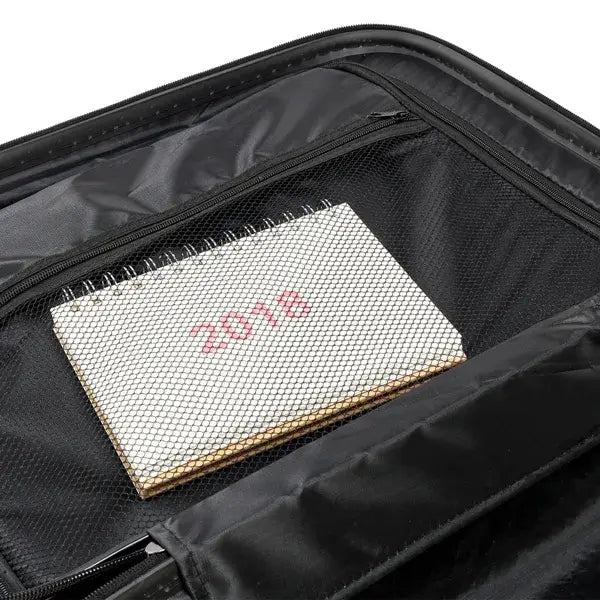 white spiral-bound notebook with red 2016 printed on the cover resting inside the black mesh-lined compartment of a 3-in-1 lightweight orange abs hard shell trolley suitcase set