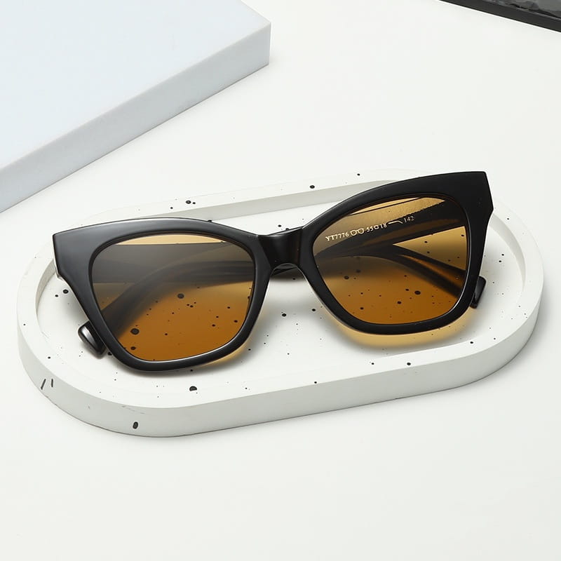 Gafas de sol de moda con forma de ojo de gato color negro con lentes tintadas ámbar y protección UV.