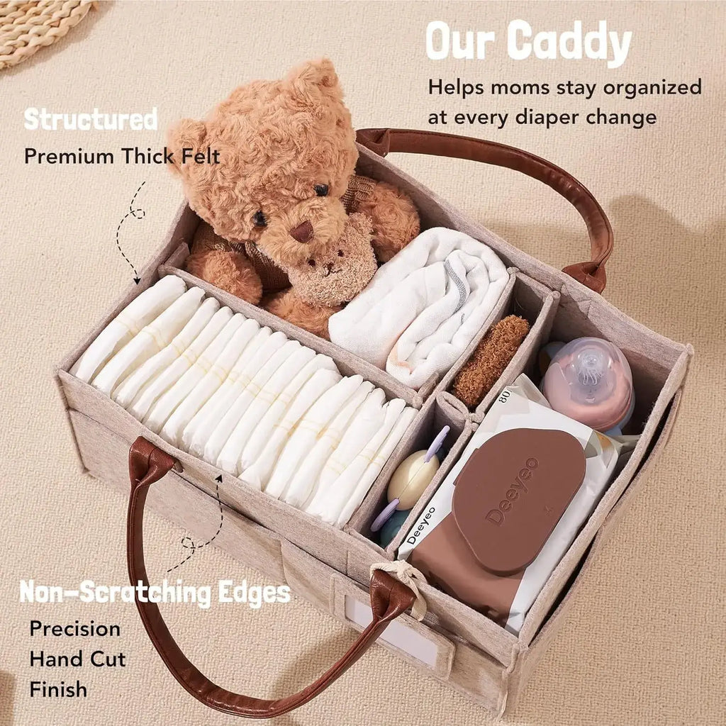 Beige felt baby diaper caddy organizer bag with brown leather handles and compartments holding diapers and baby items