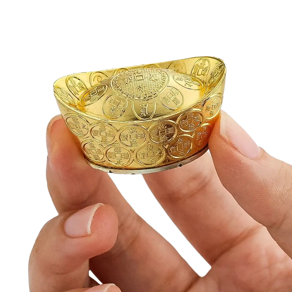 Golden intricately engraved feng shui gold ingot replica held in hand for tabletop decor and fortune figurine