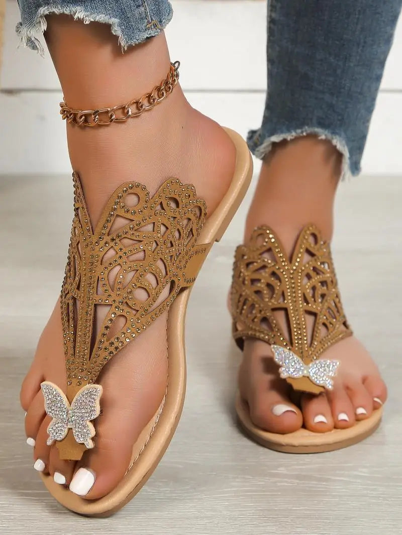 Women’s gold rhinestone hollow flat slip on sandals featuring butterfly embellishments and intricate cutout patterns.