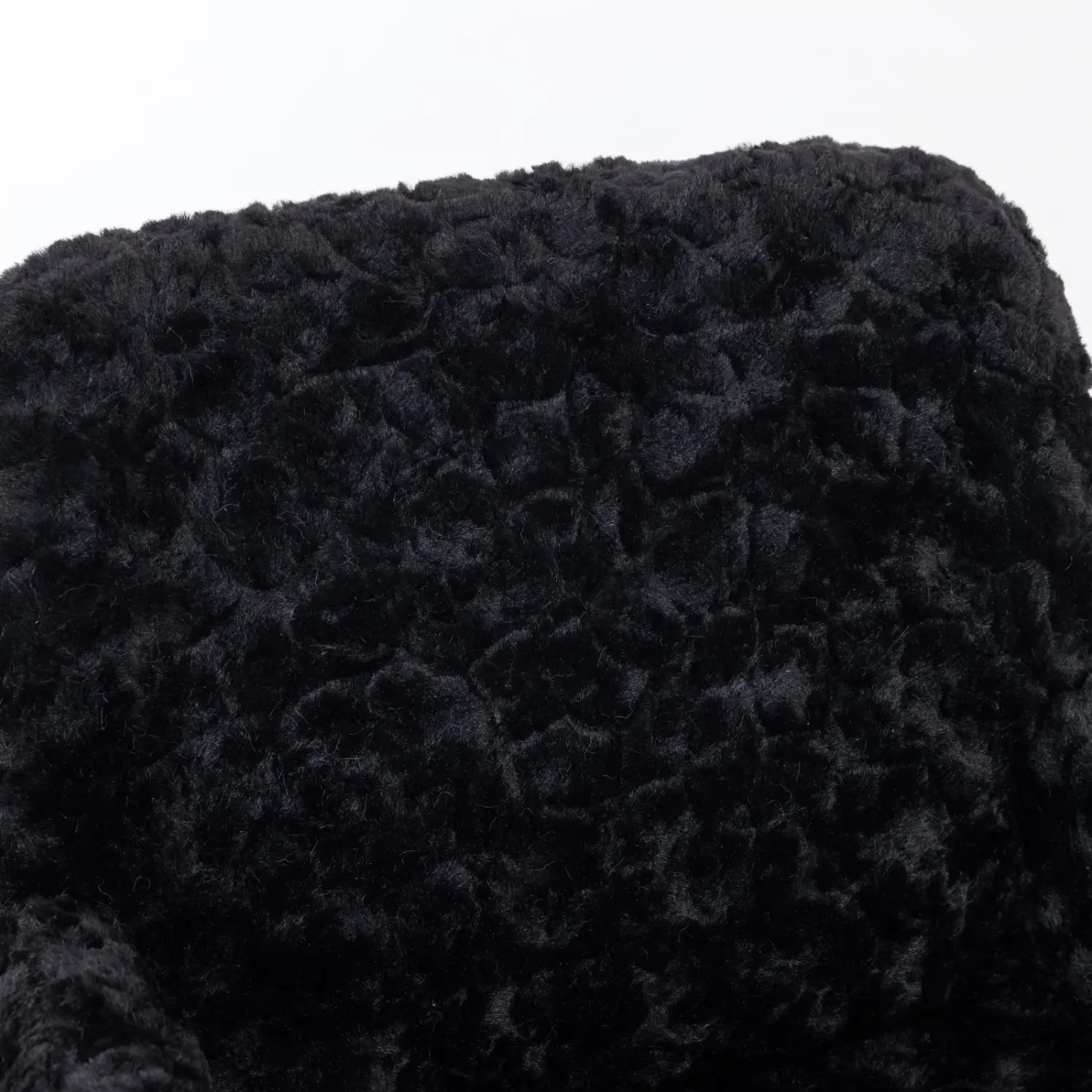 chaise de bureau en fausse fourrure noire avec base dorée, présentant un chapeau en fourrure bouclée noire duveteuse exposé sur l’assise