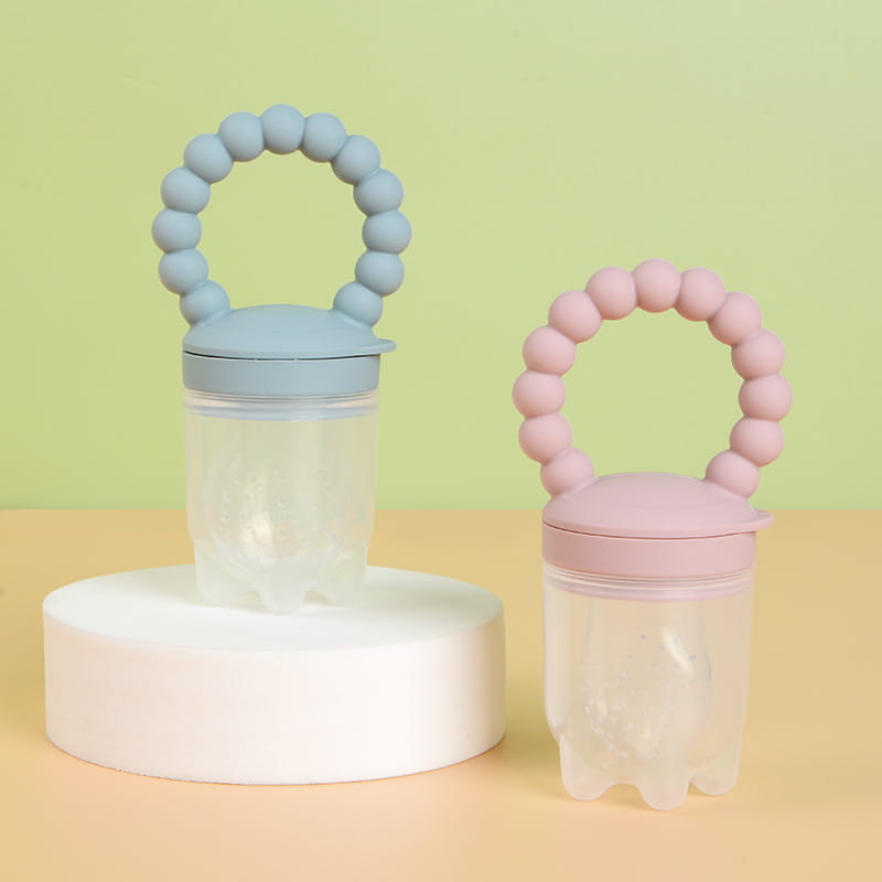 Zwei Silikon-Baby-Obstfüttergeräte und Teether-Schnuller in sanftem Blau und zartem Rosa mit Perlenringgriffen und transparenten Kunststoffkörpern zum Füttern und Zahnen von Säuglingen.
