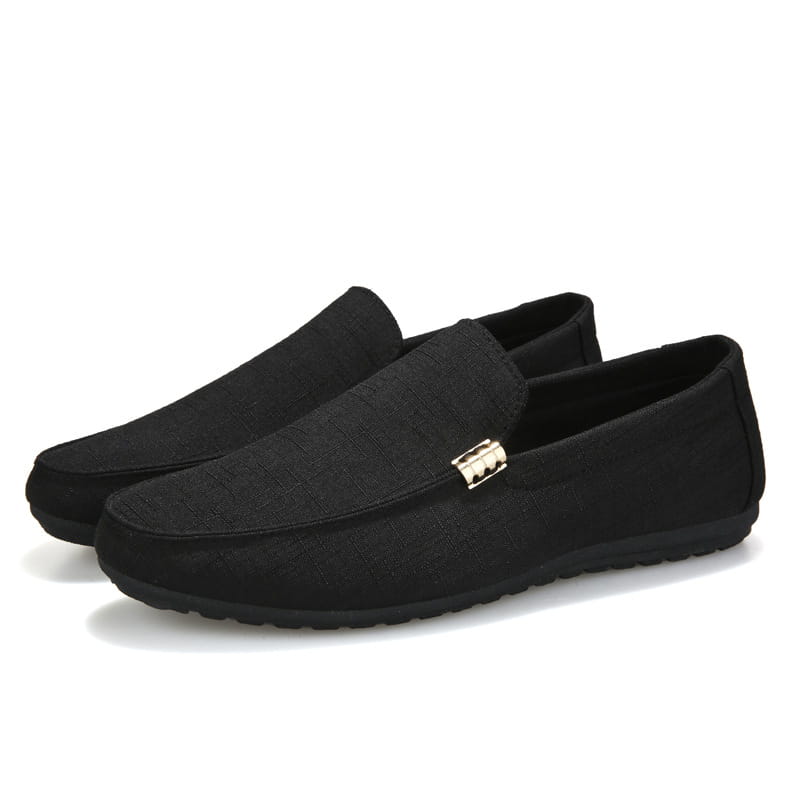 Mocassins à enfiler noirs en toile pour homme, présentant un motif discret à texture et une petite boucle métallique rectangulaire sur l’empeigne.