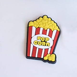 Food themed shoe charm for sandals and clogs featuring a red and white striped popcorn bucket with yellow popcorn and the words pop corn in a gold oval.