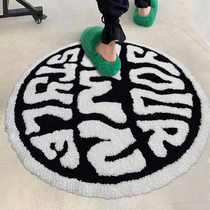 a circular black and white plush rug featuring bold textured lettering spelling your in a stylized font, designed as a minimalist print carpet for enjoying life