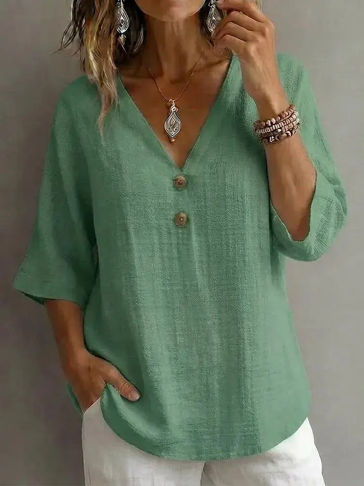 A linen v-neck button top in soft sage green with three-quarter sleeves and wooden buttons down the front featuring subtle texture.