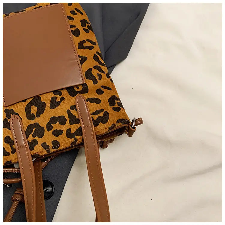 Retro leopard print suede mini bucket crossbody bag with tan leather straps and a solid brown flap.