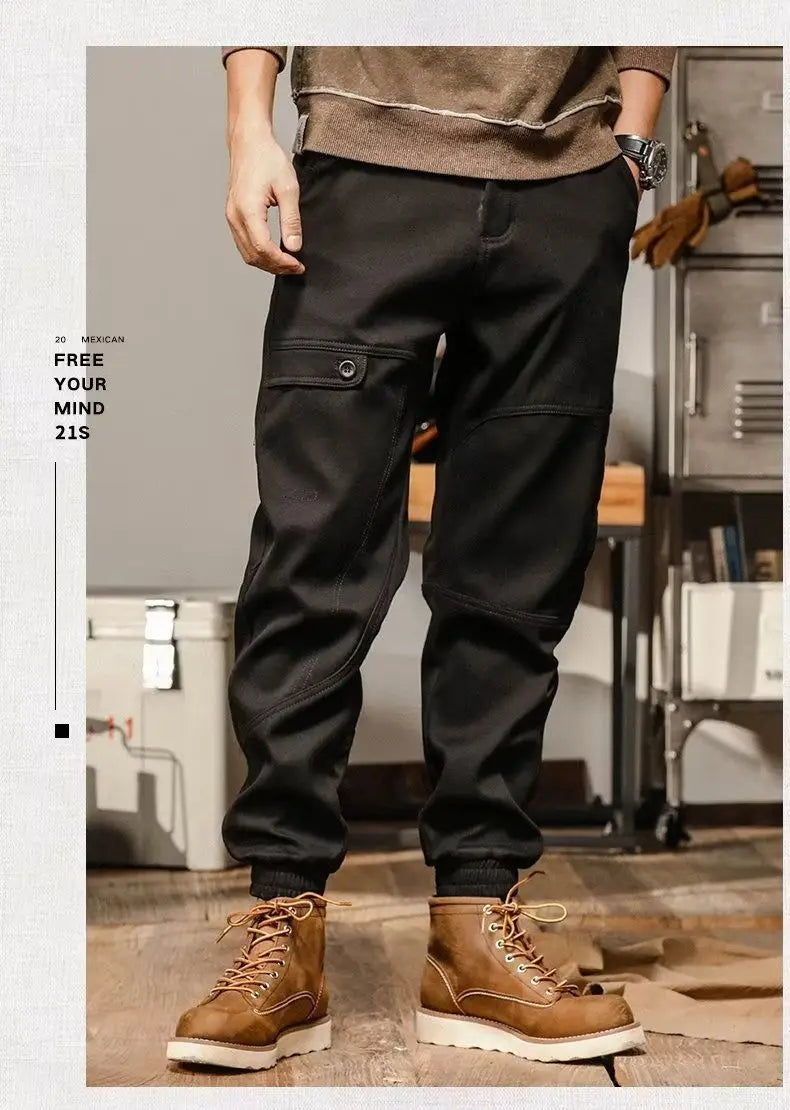 Pantalons cargo pour hommes à coupe ample, style décontracté et vêtement de travail, en noir, avec des coutures renforcées et des poches latérales portées par une personne dans un environnement de style industriel.