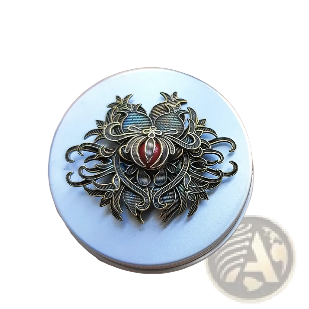 Antique bronze filigree brooch with intricate floral and pomegranate design featuring a central red gemstone accent