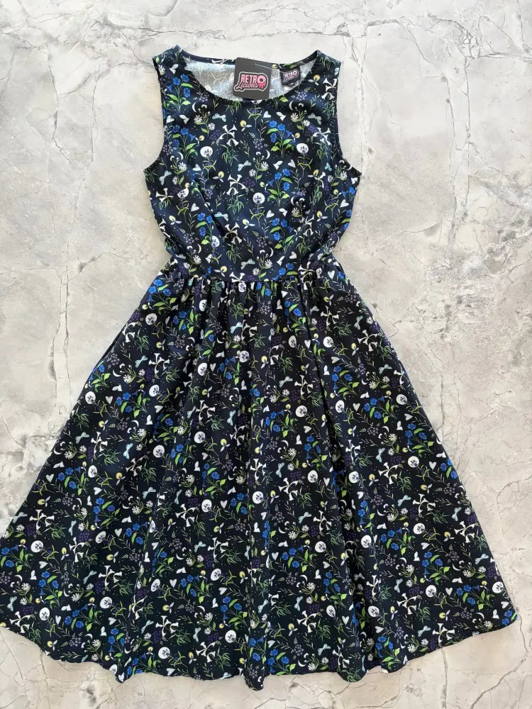 A sleeveless black cotton midi dress with white blue green floral and skull pattern featuring pockets