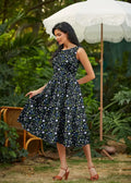 A navy blue floral print cotton sleeveless midi dress with a fitted bodice flared skirt and pockets in 1950s style