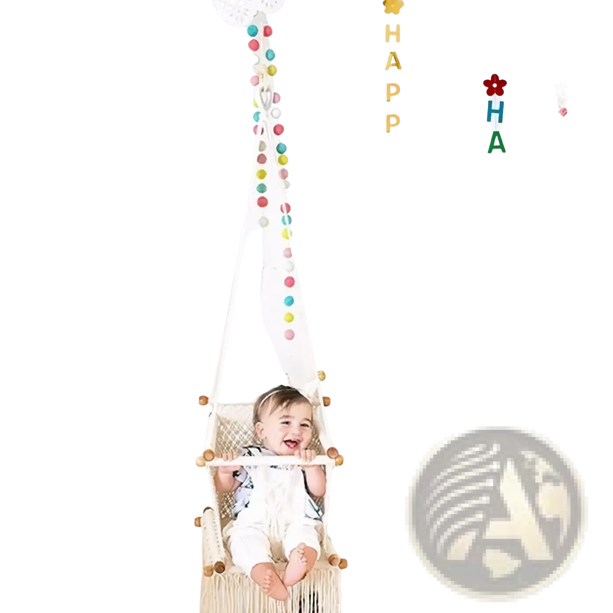 A baby sits joyfully in a cream macrame hammock swing with wooden accents for first birthday party decorations