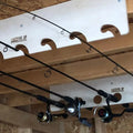 White plastic fishing rod holder with curved cutouts and hang this up branding for handcrafted wooden fishing pole storage rack