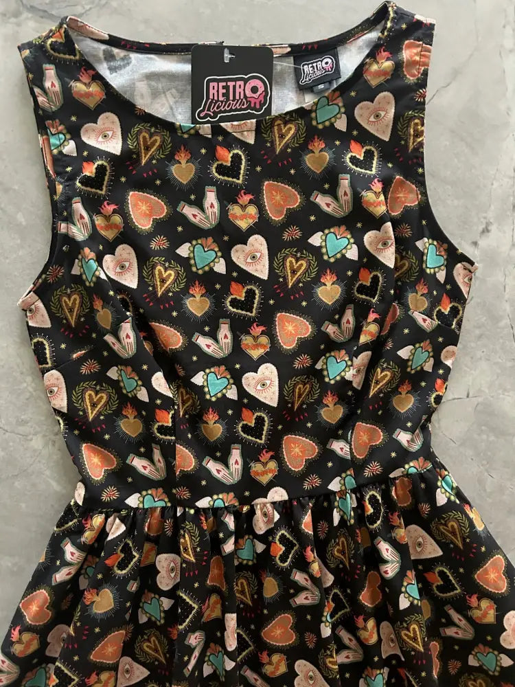 A black sleeveless cotton midi dress with colorful orange teal and gold hearts eyes and bottles featuring pockets