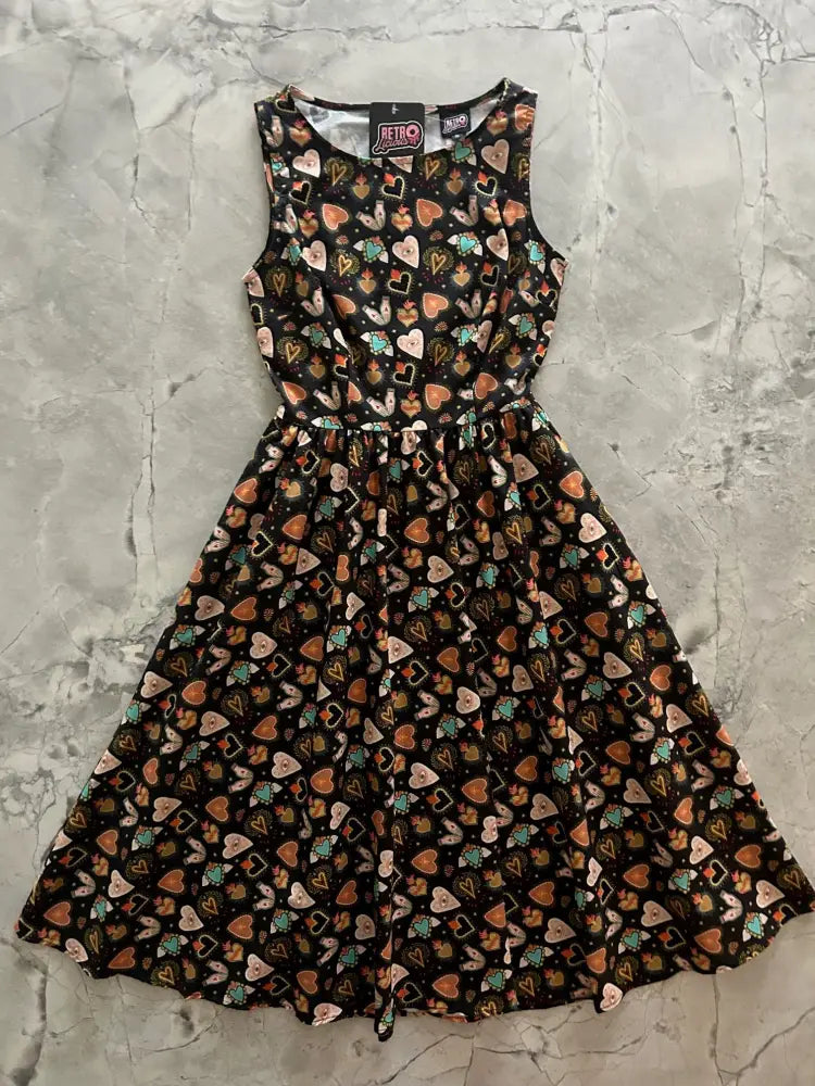 A black sleeveless flaming hearts 1950s style cotton midi dress with flared skirt multicolored heart and card patterns and pockets
