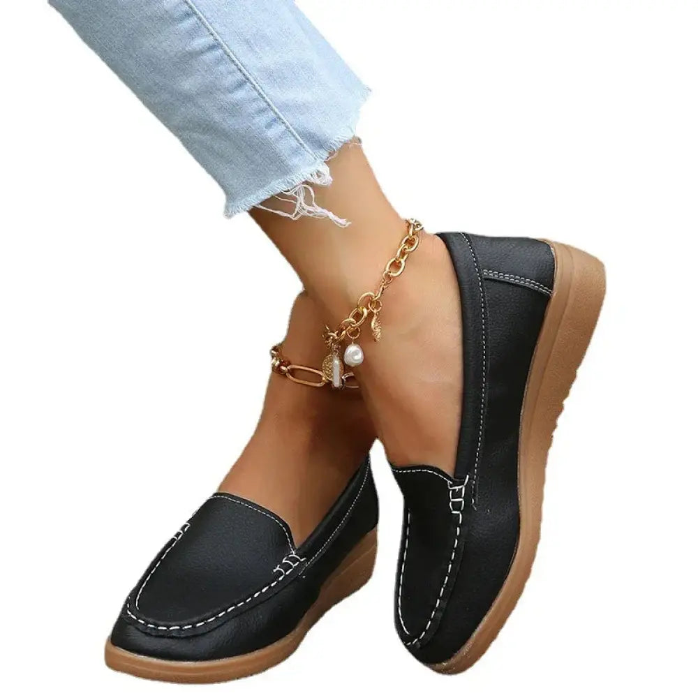 Black leather women slip on loafers with contrast white stitching and tan rubber sole for casual wear