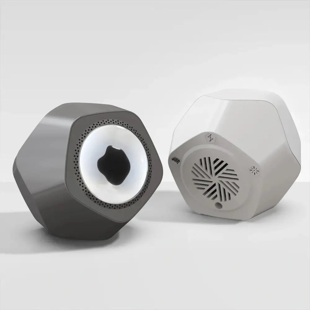 Two sleek hexagonal magnetic fluid Bluetooth speakers in matte gray and off-white with geometric design and speaker grilles